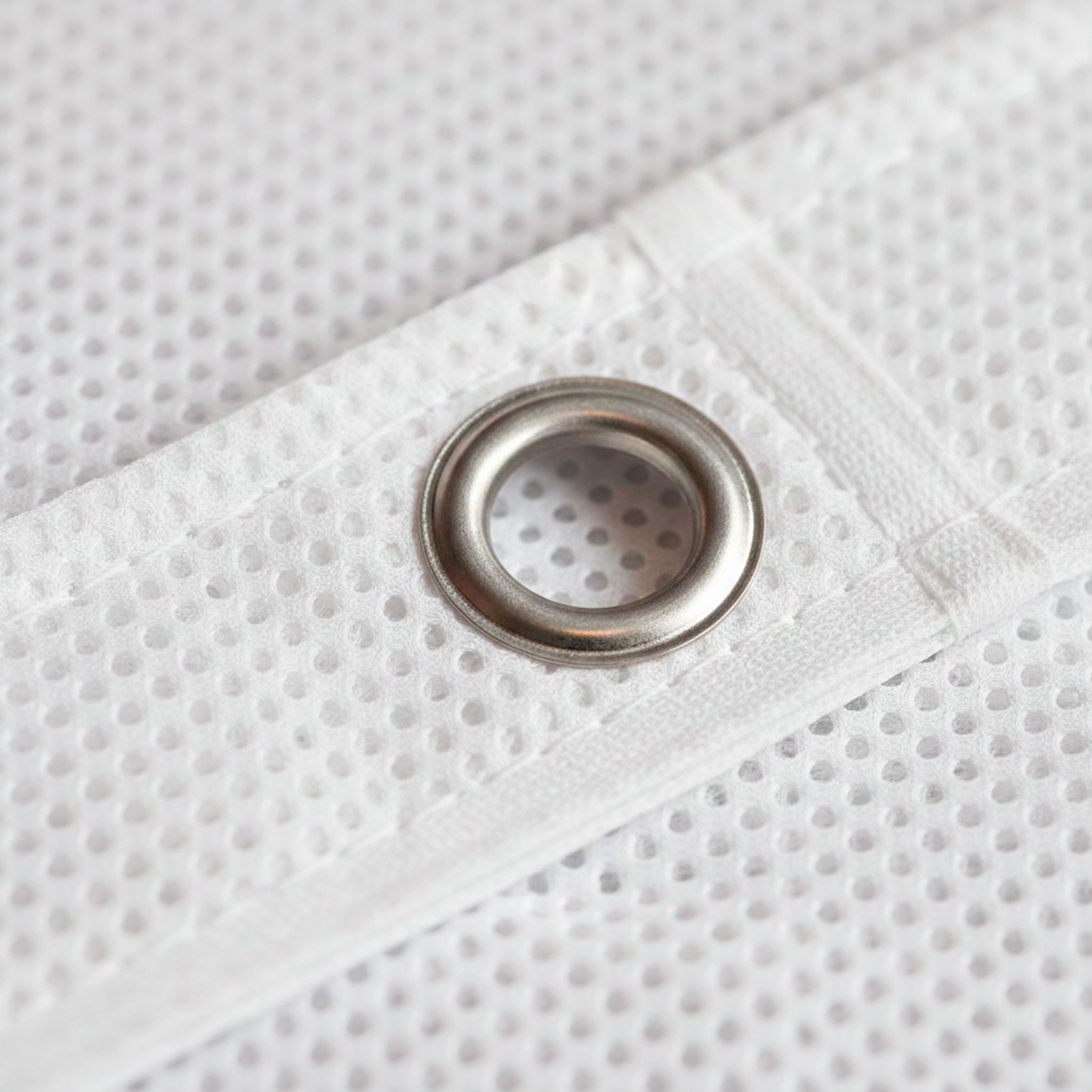 LONAS MICROPERFORADAS (MESH) - ANTIVIENTO Primer plano de lona microperforada donde se aprecia el tejido mesh y el refuerzo con ollado.